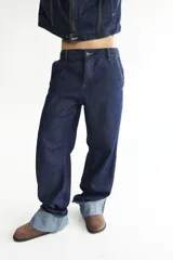 Pantalón de jean azul oscuro, de corte baggy y tiro bajo, con pespuntes a contratono color verde lima y logo bordado en el bolsillo trasero. Confeccionado en denim 100% algodón.
