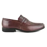 Zapato mocasín de cuero color marrón oscuro, con detalle de tira sobre el empeine y suela negra.