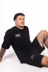 Remera oversize de algodón elastizado color negro, con diseño gráfico de alas y logo en el lateral.