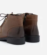 Bota de cuero marrón con caña corta, cierre de cordón y suela negra.