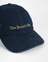 Gorra de denim azul con bordado en color dorado con la frase "The Brunch Club".