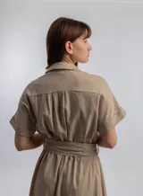 Vestido camisero midi color beige, con cuello camisero, mangas cortas con dobladillo, cierre frontal con botones y lazo para ajustar en la cintura.