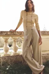 Top color beige de punto fino, con cuello barco y manga larga.