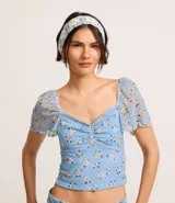 Blusa cropped de tule celeste con estampado floral, escote corazón, mangas cortas sueltas con acabado frufru y fruncido en el busto.