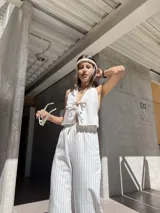 Conjunto de top y pantalón a rayas verticales color beige y blanco. El top es halter con lazos en el frente y el pantalón es de corte ancho.