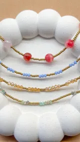 Set de cuatro pulseras elásticas con cuentas de piedra natural ágata de colores rosa, rojo, celeste, amarillo y verde, y pequeñas cuentas doradas de acero.