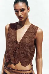 Top chaleco marrón de crochet con escote en pico y cierre frontal con lazos.