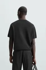 Camiseta negra de corte recto y manga corta, tejida en punto perlado de algodón.