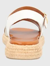 Sandalia con tiras cruzadas doradas con textura de piel de serpiente y ajuste con hebilla en el tobillo. Base tejida tipo esparto y plantilla acolchada.