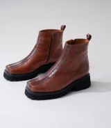 Botas cortas color marrón de cuero vacuno con suela track negra de goma. Presentan cierre lateral con cremallera YKK y puntera cuadrada.
