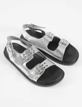 Sandalias plateadas con tiras anchas y plantilla cómoda, con tira ajustable en el talón. Fabricadas en cuero vegano.