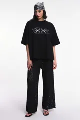 Pantalón de tejido calado color negro, de corte palazzo y cintura alta con elástico.