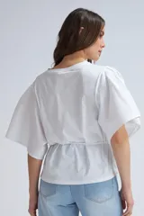 Camiseta blanca de algodón con mangas abullonadas y lazo ajustable en la cintura.