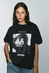 Remera negra de algodón con efecto lavado, cuello redondo y mangas cortas. Estampado frontal con imagen de Lady Gaga y texto "LVDY GAGA" y "MAYHEM".
