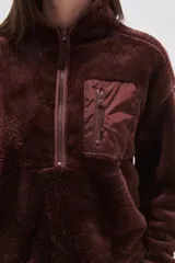 Buzo de polar tipo sherpa en color crudo, con cuello alto y cierre frontal parcial. Presenta un bolsillo de parche con cierre en el pecho y mangas largas de calce holgado.