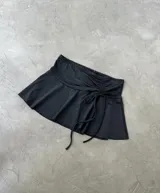 Minifalda negra con cintura ancha, fruncido lateral y cordones ajustables.