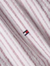 Camisa Tommy Hilfiger de corte regular, confeccionada en tejido mil rayas ligeramente elástico. Diseño a rayas verticales color blanco y rojo, cuello mao y logo de Tommy Hilfiger bordado en el pecho.