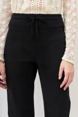 Pantalón tipo babucha negro, confeccionado en gabardina elastizada, con cintura regulable mediante cordón y puños ajustados en flame. Posee bolsillos diagonales delanteros y bolsillos con solapa y botón traseros.