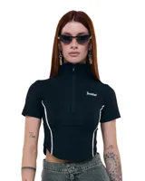 Top negro cropped de gabardina elastizada, con cuello alto, cierre frontal y mangas cortas. Diseño entallado con recortes y costuras a contratono blancas. Logo Temblad en el pecho.