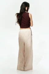 Top marrón sin mangas, de punto texturizado, con escote bote y cordones ajustables en un lateral y en un hombro.