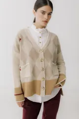 Cárdigan color beige con patrón de rombos en tonos marrones, cierre con botones, bolsillos frontales y bordados de cerezas.