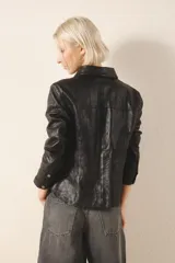 Camisa de cuero ovino color negro, de corte jeanero, con bolsillos tipo ojal en el delantero y cierre frontal con broches a presión con el logo de Rapsodia.