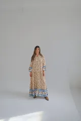 Vestido largo color beige con estampado abstracto en tonos marrones y azules, con cuello mao, mangas largas con puños elásticos y cierre frontal con botones.