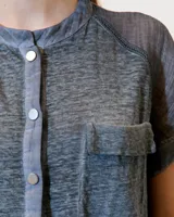 Remera celeste de lino y ramio, con corte boxy, manga japonesa, cuello mao, media cartera con broches metálicos y bolsillo plaqué con efecto de tapa.