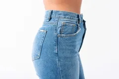 Pantalón de jean azul de tiro alto con corte irregular en la cintura y cierre con doble botón.