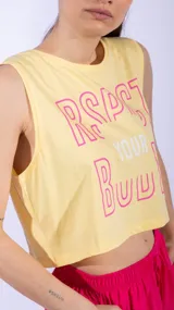 Top deportivo corto color rosa fucsia, sin mangas y con cuello redondo. Estampado frontal con el texto "Respect Your Body" en letras amarillas con contorno y la palabra "Your" en blanco.