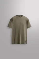 Camiseta deportiva de entrenamiento, corte regular fit, color gris claro, con cuello redondo y manga corta. Confeccionada en tejido técnico ligero y elástico con estructura Quick Dry nivel 2. Presenta costuras planas y un pequeño logo estampado en la parte inferior derecha.