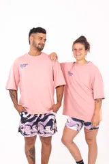 Remera oversize rosa con estampado en la espalda que incluye texto y una ilustración de dos personas cayendo.