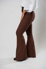 Pantalón marrón de tiro alto con cierre frontal de cremallera y botón. Tiene bolsillos delanteros y traseros, y corte acampanado.