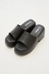 Sandalias negras con plataforma y tira ancha sobre el empeine.