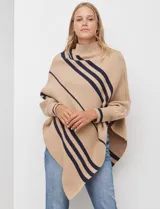 Poncho de tejido color beige con cuello alto y rayas diagonales anchas en azul marino. Presenta mangas largas y terminación asimétrica.