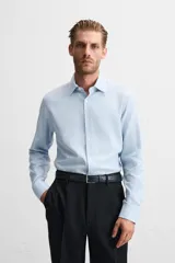 Camisa blanca de corte regular, cuello italiano, manga larga con puños abotonados y cierre frontal con botones.