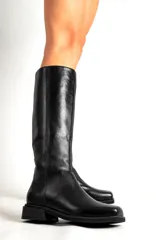 Botas de cuero de caña alta, con punta cuadrada y taco bajo. Disponibles en color bordó y negro.