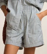 Short de sarga con estampado de rayas verticales en tonos celeste y blanco, con cintura elástica, bolsillos delanteros y traseros, y bajo plegado.