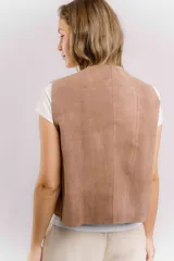 Chaleco de cuero color marrón con estampado brillante, de corte recto y largo a la cintura. Su diseño abierto en el frente lo convierte en una prenda versátil, fácil de combinar tanto con básicos como con looks más elaborados.