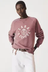 Sudadera lila de algodón con cuello redondo y mangas largas. Estampado en el frente con el logo "Zara A Coruña" y el texto "Est. 1975".