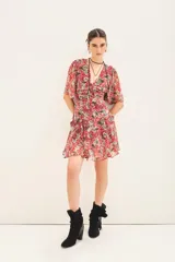 Vestido corto con estampado floral en tonos rojo, gris y blanco. Tiene escote en V, mangas cortas con volados, frunces en el delantero y espalda, bolsillos delanteros y cierre invisible.