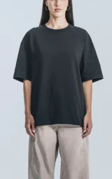 Remera negra de corte crop y calce oversize, con hombros caídos y cuello redondo.