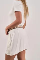 Vestido corto de manga corta, color blanco, con cuello redondo y corte holgado. El tejido parece ser modal o una mezcla ligera y fluida.