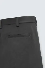 Pantalón chino de vestir negro, corte slim fit, con bolsillos laterales y traseros. Cierre frontal con cremallera y botón.