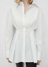 Camisa blanca de corte recto con cuello camisero, mangas largas con puños abotonados y cierre frontal oculto con botones.