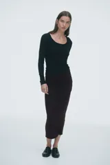 Pollera tobillera color marrón chocolate, de punto con elástico oculto en la cintura y frunces a la altura de la cadera para crear una silueta levemente drapeada.