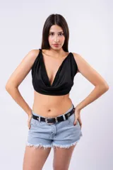 Top negro ajustado con escote drapeado tipo cowl neck y cuello halter. La tela presenta pequeños apliques brillantes distribuidos por toda la superficie.