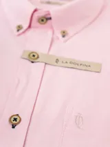 Camisa de manga larga blanca, confeccionada en tejido oxford, con cuello abotonado (button-down) y bolsillo en el pecho.