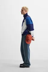 Chaqueta deportiva azul marino, azul y blanca con cierre frontal, cuello alto y bolsillos laterales.