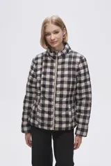 Campera puffer estampada a cuadros en blanco y negro con pequeños corazones rosados, cierre frontal con cremallera y bolsillos laterales.